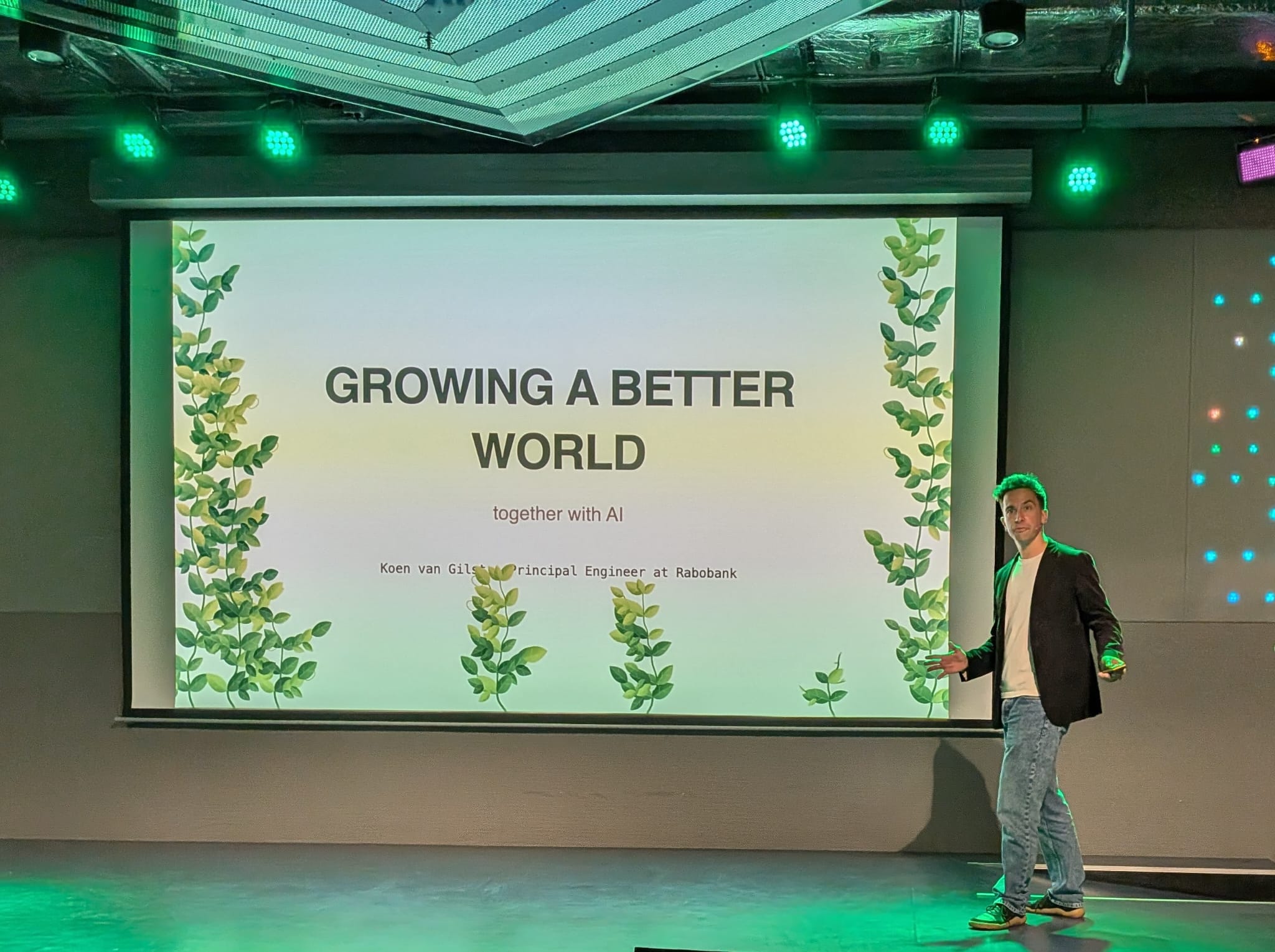 Speaking on stage at Frontmania beside a slide titled Growing a Better World Together with AI